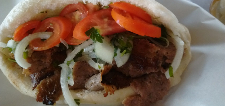 A doner kebab in pita bread with pickles ready for delivery